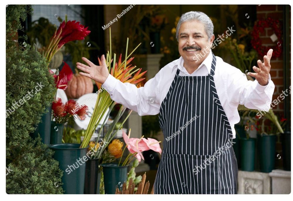 A watermarked stock photo of an older Italian gentleman in an apron, a shop owner of some kind, stepping up with a smile and his arms open in greeting. It’s the same picture every day. Today he is "working for the weekend"!