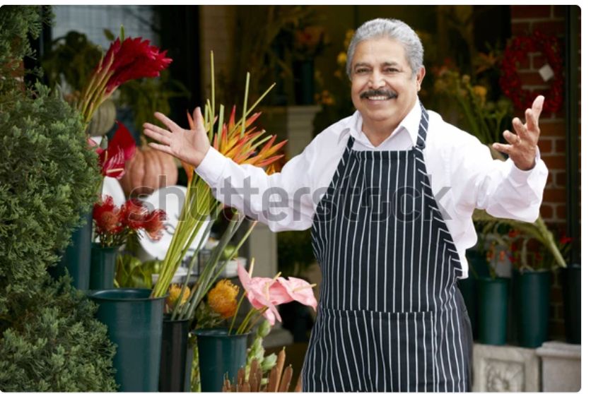 A watermarked stock photo of an older Italian gentleman in an apron, a shop owner of some kind, stepping up with a smile and his arms open in greeting. It’s the same picture every day. Today he is giving out glasses for the eclipse!