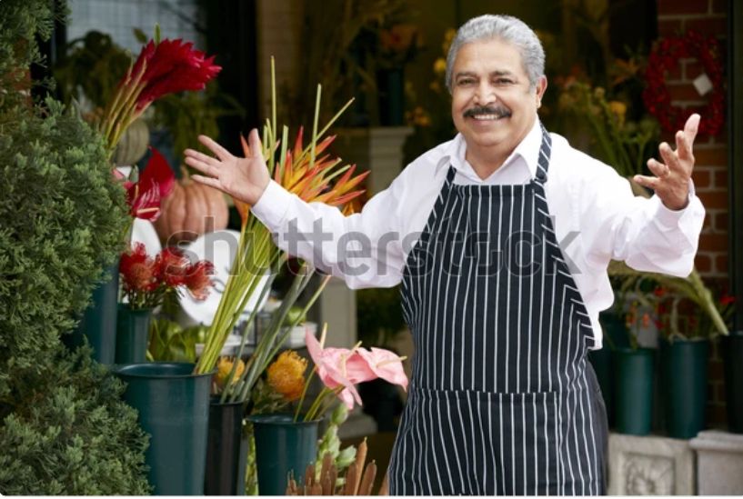 A watermarked stock photo of an older Italian gentleman in an apron, a shop owner of some kind, stepping up with a smile and his arms open in greeting. It’s the same picture every day. Today he is practicing his ukulele!
