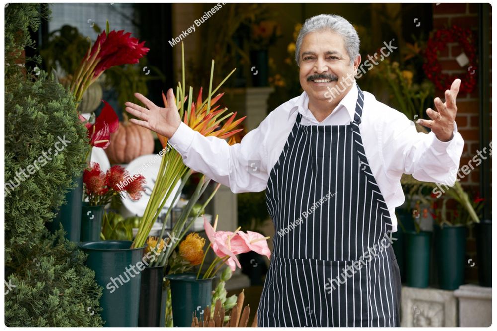 A watermarked stock photo of an older Italian gentleman in an apron, a shop owner of some kind, stepping up with a smile and his arms open in greeting. It’s the same picture every day. Today he is sweeping!