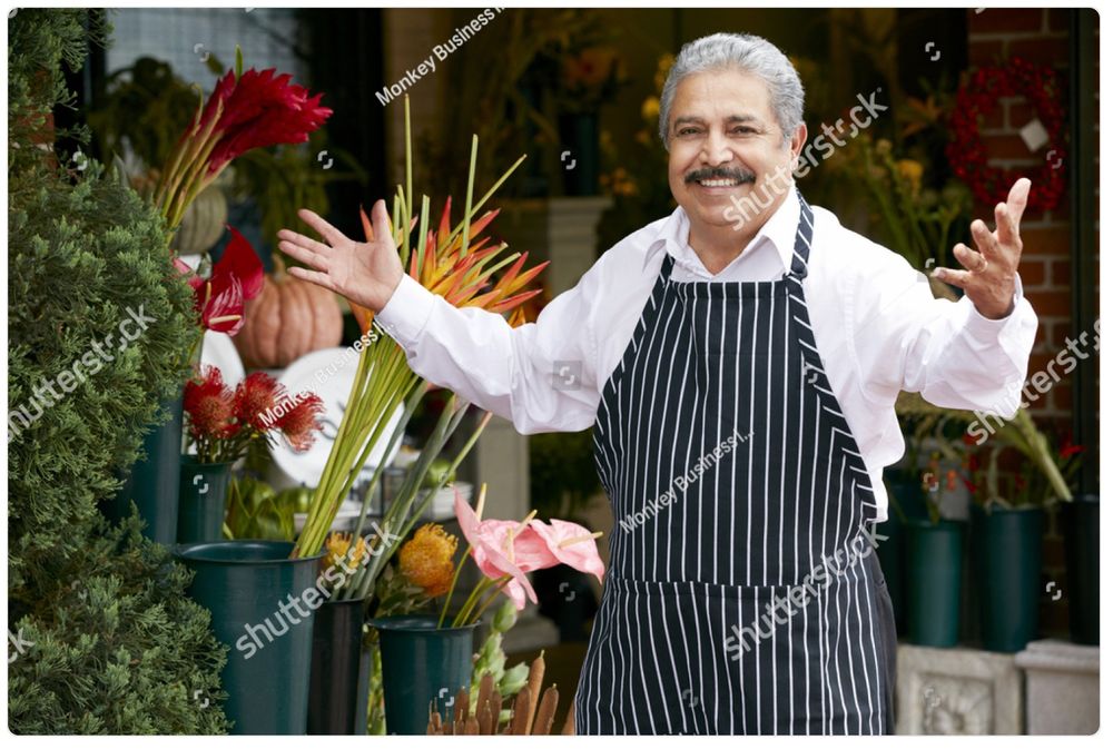 A watermarked stock photo of an older Italian gentleman in an apron, a shop owner of some kind, stepping up with a smile and his arms open in greeting. It’s the same picture every day. Today he has coffee already brewing for you!
