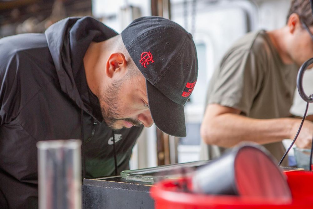 A scientist in a jacket and baseball cap peers into a tray of zooplankton