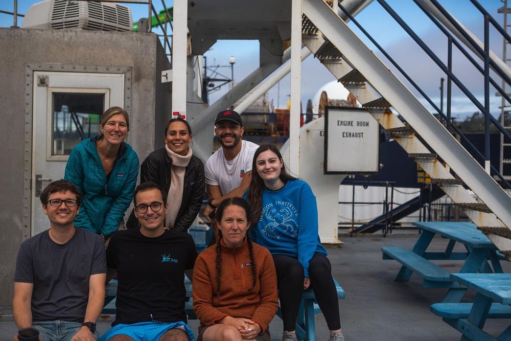 Scientists and artists smile for the camera outside aboard the research cruise