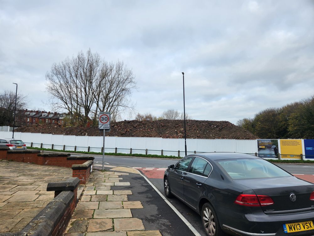 Large cordonned off area with 20ft high pile of dirt and rubble.