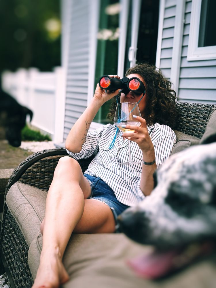 Me sitting on an outdoor couch drinking a glass of white wine surrounded by two dogs. I’m using a pair of binoculars to spy on my local murder of crows that I’m slowly gaining the trust of through daily offerings of peanuts and cat food. 