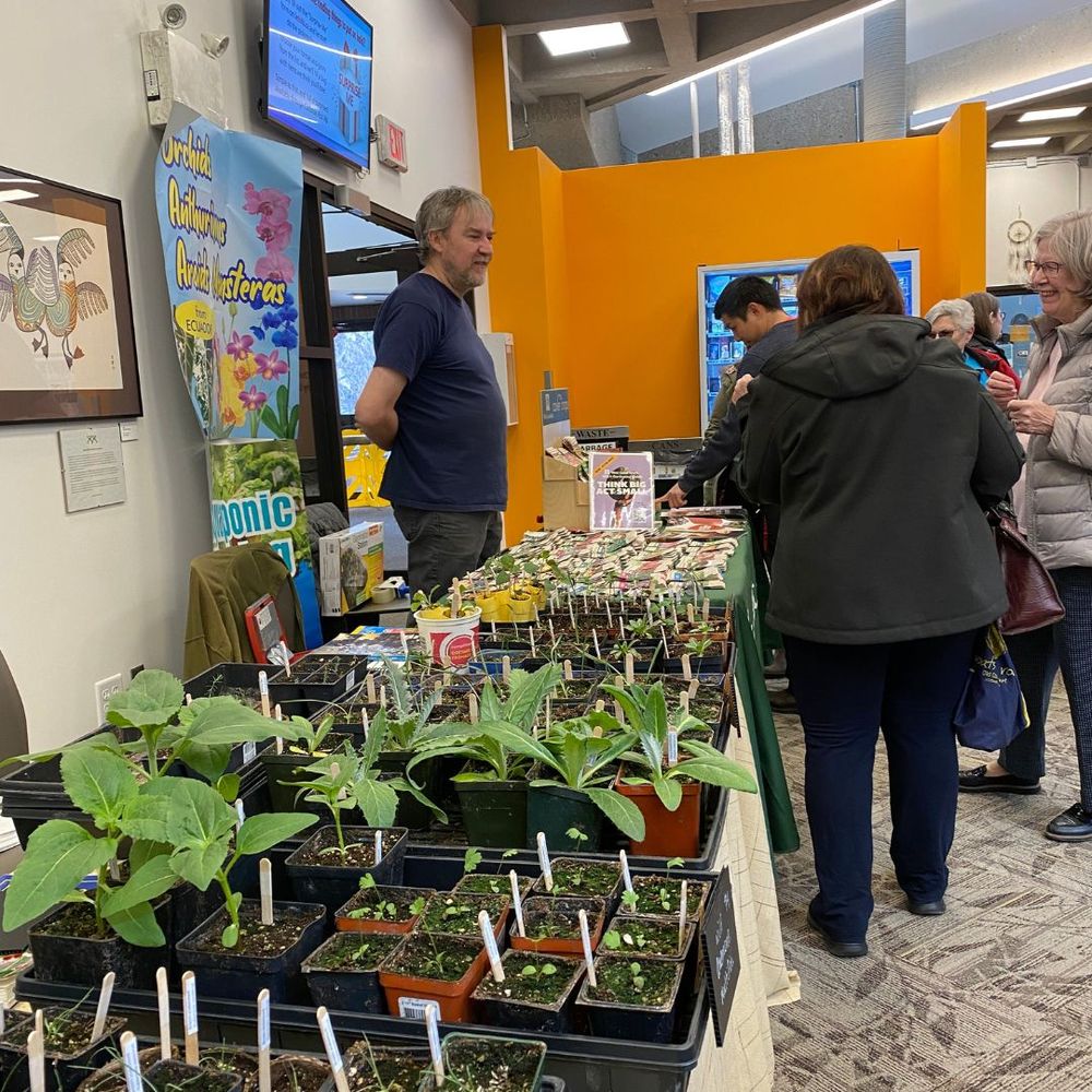 Visitors gather around a booth selling seeds and garden plants.