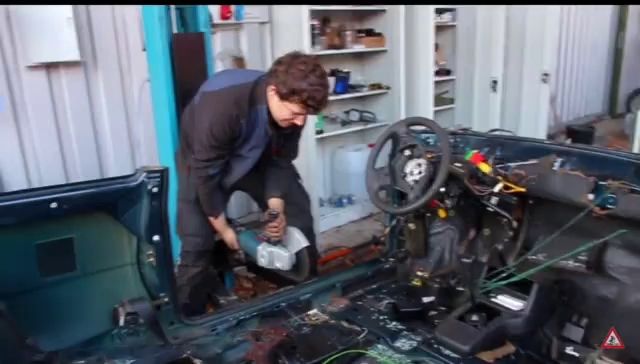 a man is working on the inside of a car with a warning sign in the corner