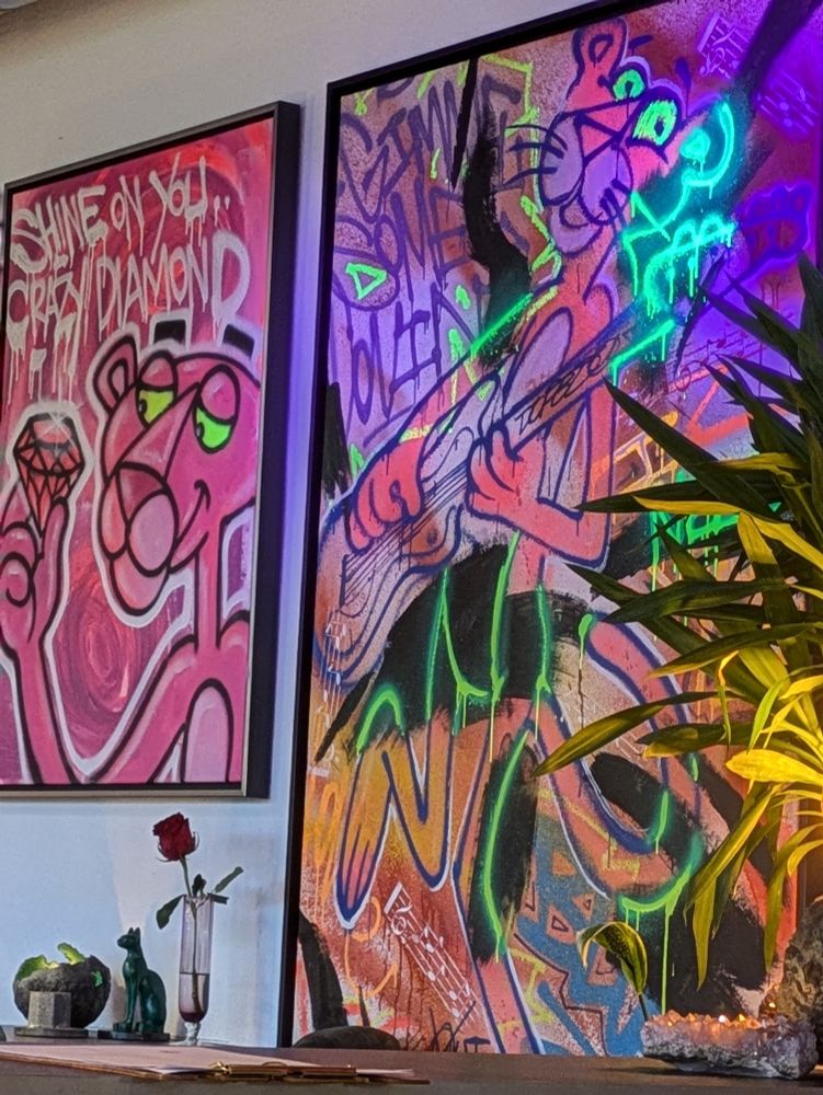 Two paintings of the Pink Panther. The left depicts him holding a diamond, text reads 'Shine on you... crazy diamond.' The left depicts him playing a guitar, text reads 'Gimme some loving.' Some of the paint is glowing under blacklight.