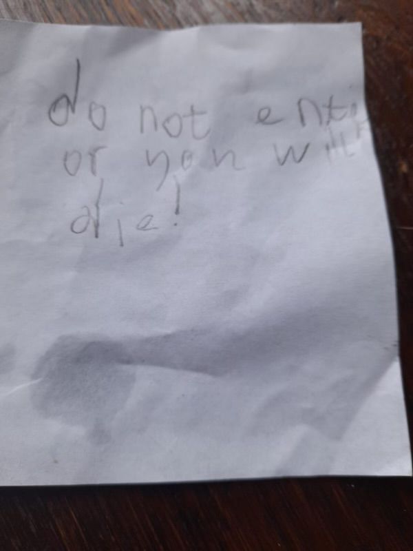 A piece of paper with the message ‘do not entir or you will die!’ In child’s handwriting