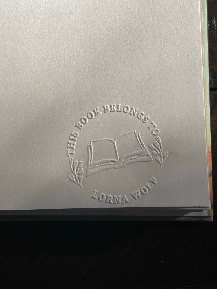 An embossed library stamp on the endpaper that reads “this book belongs to Lorna Wolf.” There is an open book in the center of the stamp flanked by flowers on either side. I need an embosser. I’d emboss everything:  paper plates, toilet paper like fancy hotels do, the water bill. 