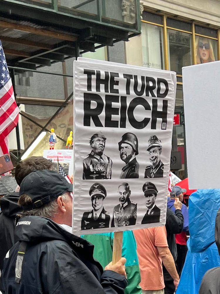 Printed sign with “The Turd Reich” and pictures if Trump, JD Vance, Nigel Farage, Elon Musk, Benjamin Netanyahu, and Vladimir Putin