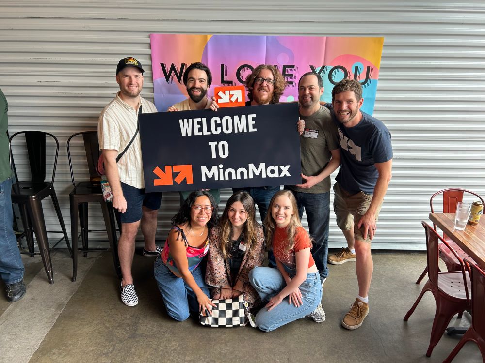 Most of MinnMax holding a welcome to MinnMax sign