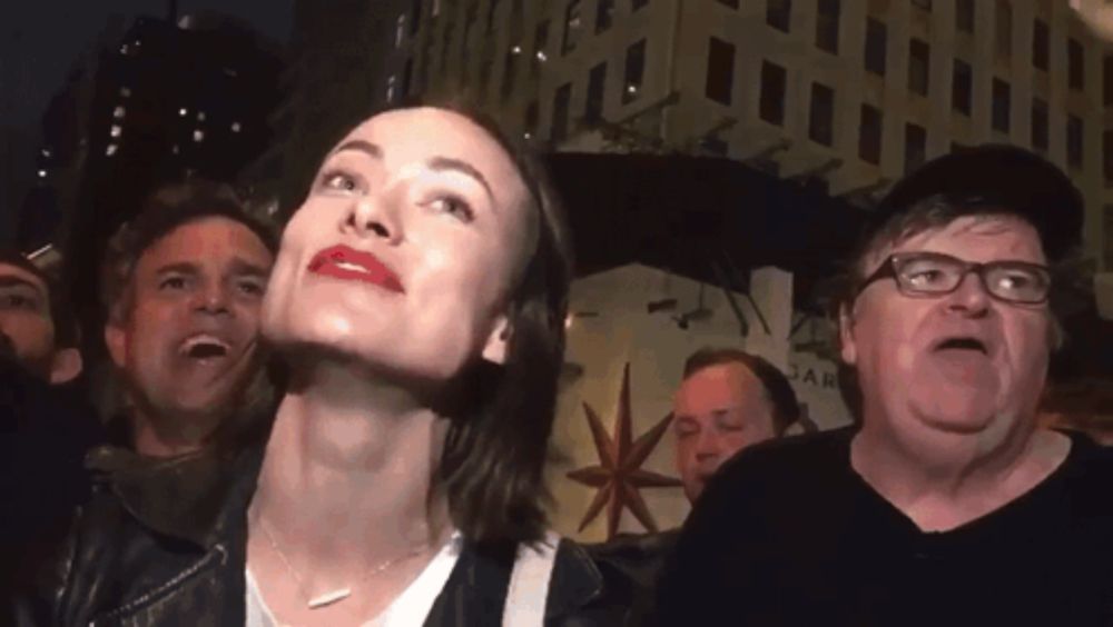 a group of people are standing in front of a building with a star on it and one man is making a funny face