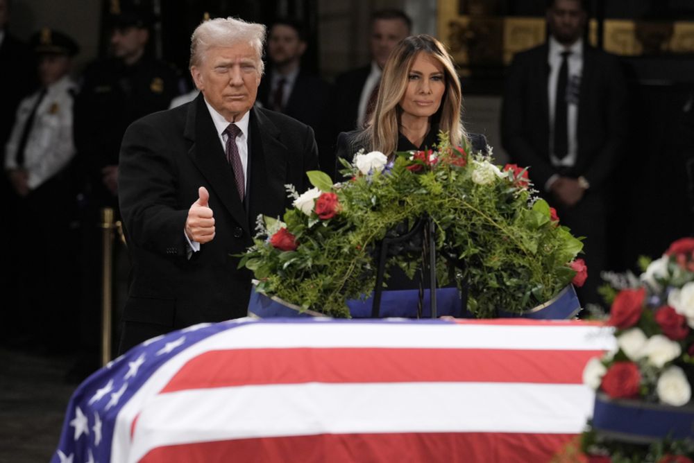 Donald Trump giving a thumbs up beside Jimmy Carter's casket. 