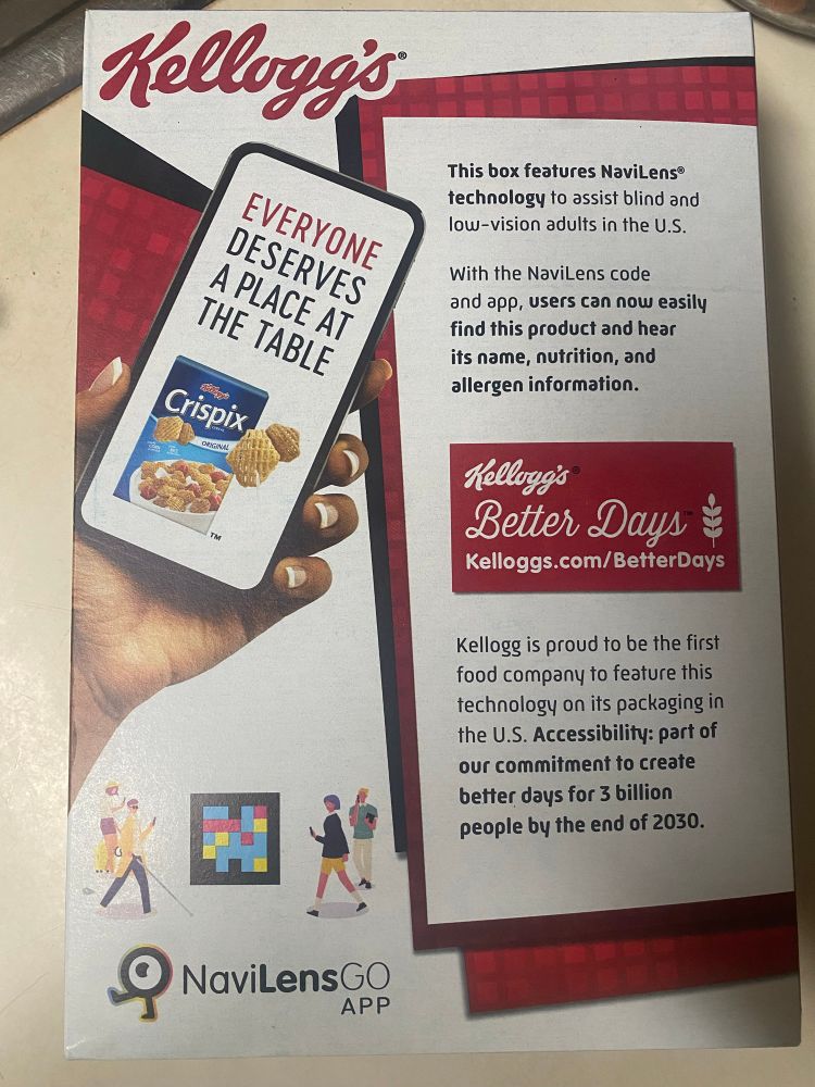Alt text: The back of a Crispix cereal box. There is an advertisement for an app called NaviLens which is meant to be an accessibility aid. The text of the advertisement is: Everyone deserves a place at the table. This box features NaviLens® technology to assist blind and low-vision adults in the U.S. With the NaviLens code and app, users can now easily find this product and hear its name, nutrition, and allergen information. Kellogg's Better Days Kelloggs.com/BetterDays Kellogg is proud to be the first food company to feature this technology on its packaging in the U.S. Accessibility: part of our commitment to create better days for 3 billion people by the end of 2030.