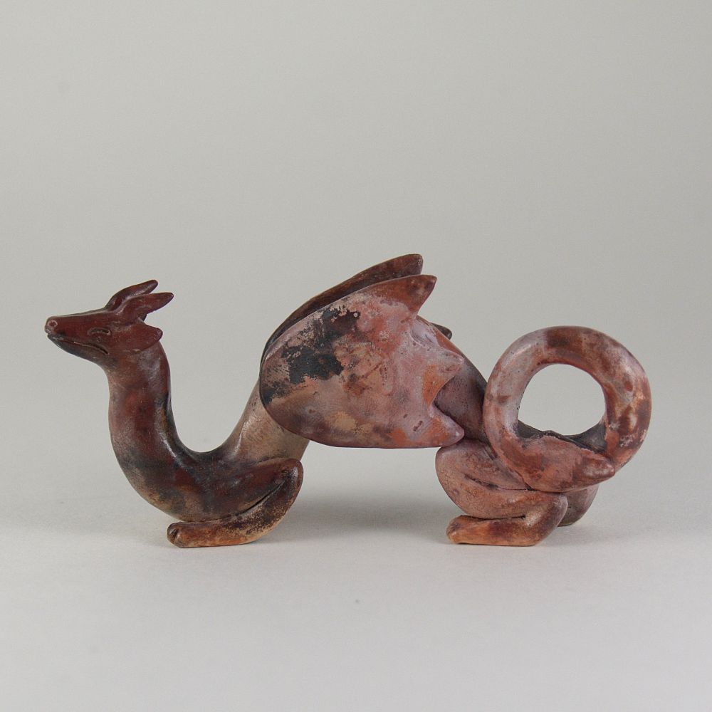 A photo of a ceramic dragon sculpture on a white background. The dragon is colored with mottled blotches of pink, burgundy, peach, and black.