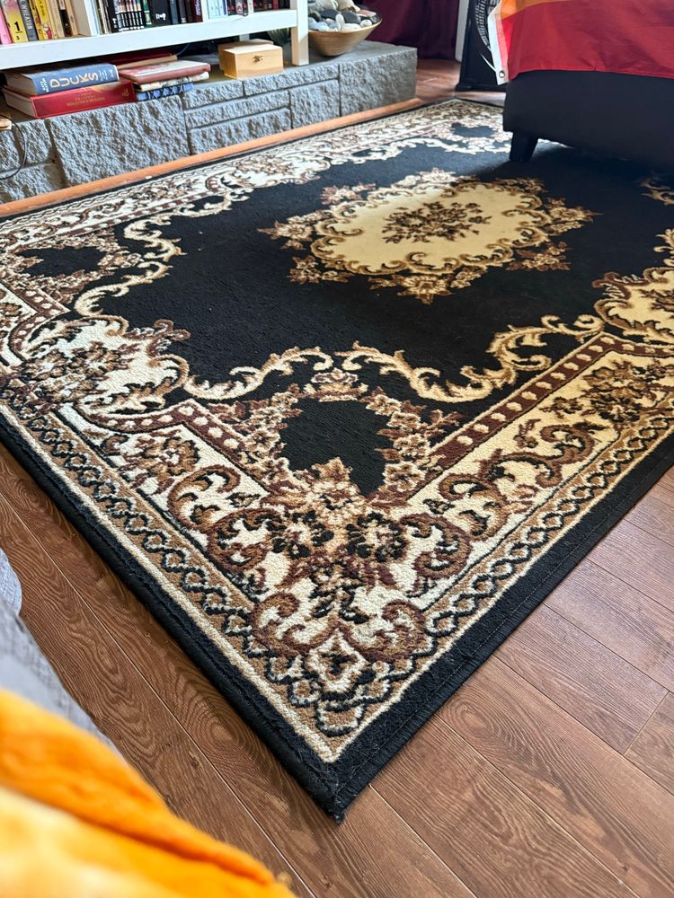 A black rug with brown and white patterns that temporarily isn’t covered in orange cat hair. 