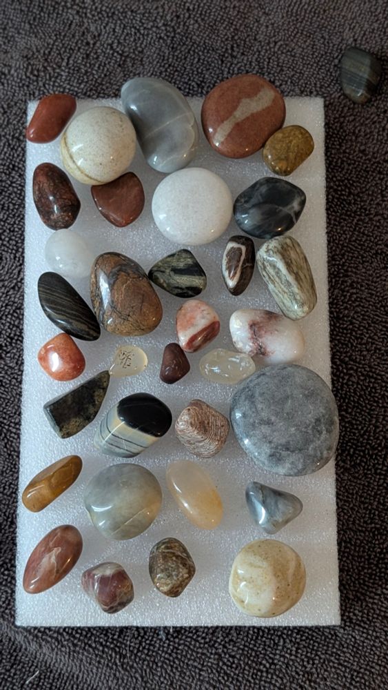 Several shiny rocks arranged on a piece of white closed cell foam. 