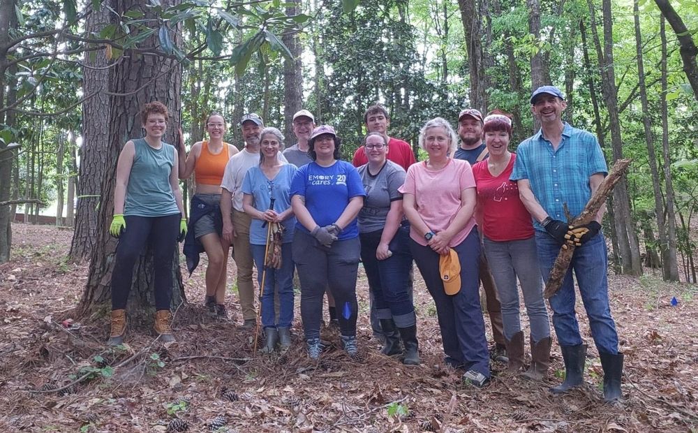 12 volunteers standing in a wooded historic cemetery