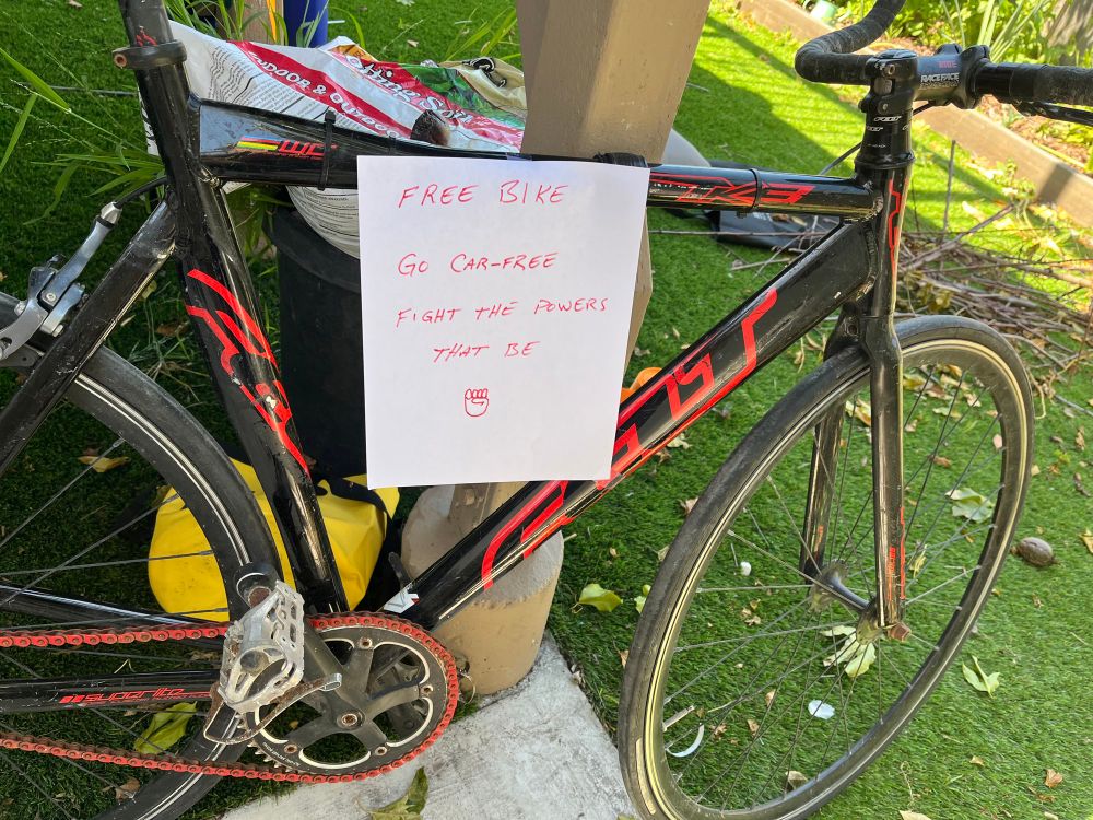 Image of a Felt track bike in giving away. With a note attached: “Free bike. Go car-free, Fight the powers that be”