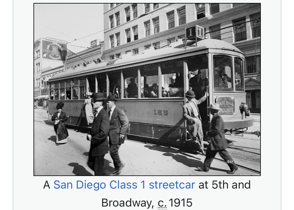 San Diego streetcar from 1915 with men in suits and bowler hats hopping on/off