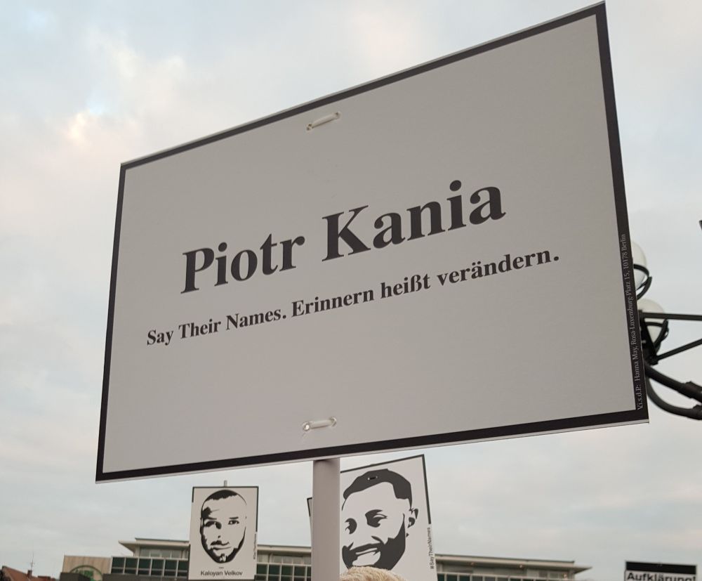 Foto zeigt ein Schildmit dem Namen Piotr Kania und dem Schriftzug "Say Their Names. Erinnern heißt verändern" auf der Gedenkdemo in Hanau im Februar 2024