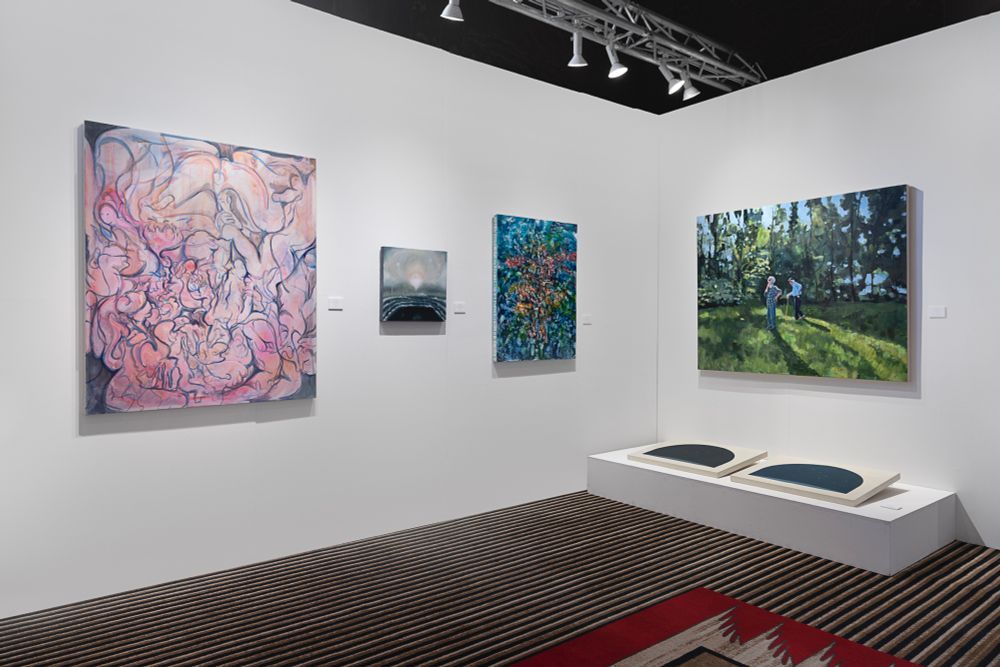 Angle view of an art fair booth with color paintings. 