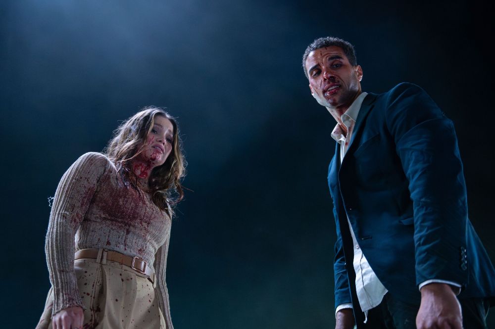 A woman and a man, both looking like the kind of cute folks who would star in a rom-com, look down at the camera while covered in blood. They are adorable! And exhausted. Probably from fighting off a slasher the whole time after their meet cute.