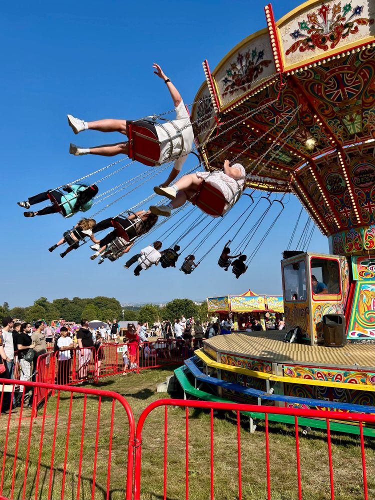 A chair swing ride in action at the fair against a blue summer sky.