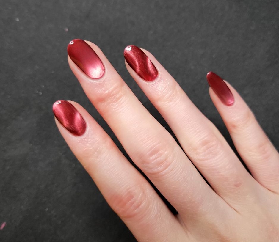 right hand nails - red magnetized glass bead style on middle and pinky, magnetized with two partial circles in opposite corners of the nail on index and ring fingers.