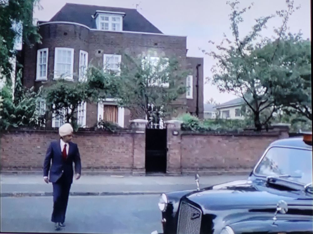 A man in a turban leaves a large house in London
