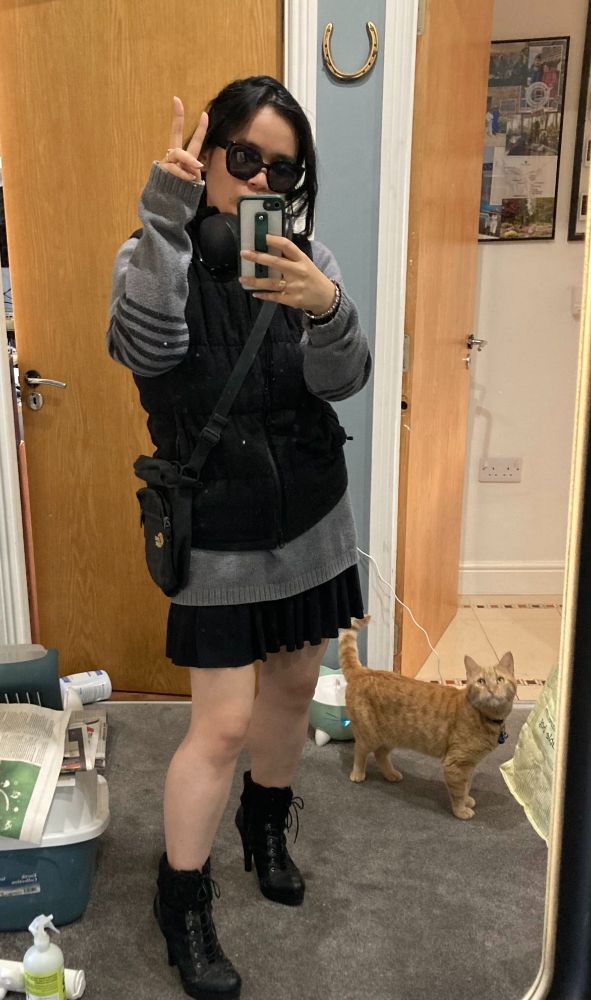 Úna-Minh dressed in more techwear style clothing as her cat BB looks on