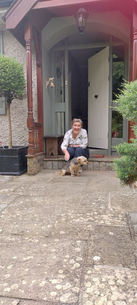 Ruth sitting on the doorstep laughing with the small dog