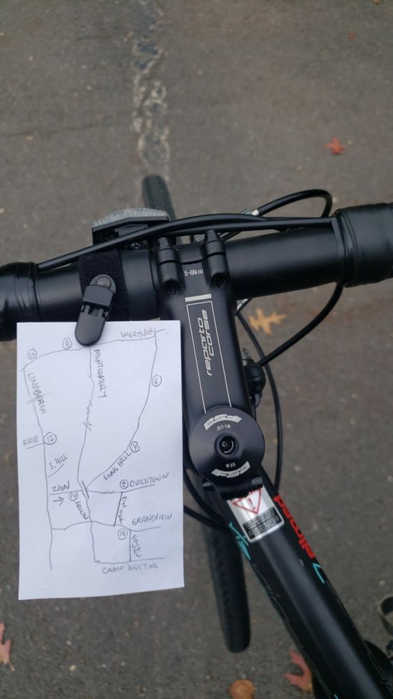 A photo of an index card clipped to the handle bars of a black road bike. The card has a hand-drawn map of a seventeen mile route through the Sourlands of New Jersey.