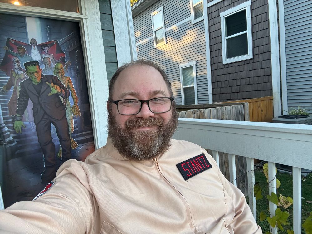 Middle aged, bearded white man in a ghostbusters costume