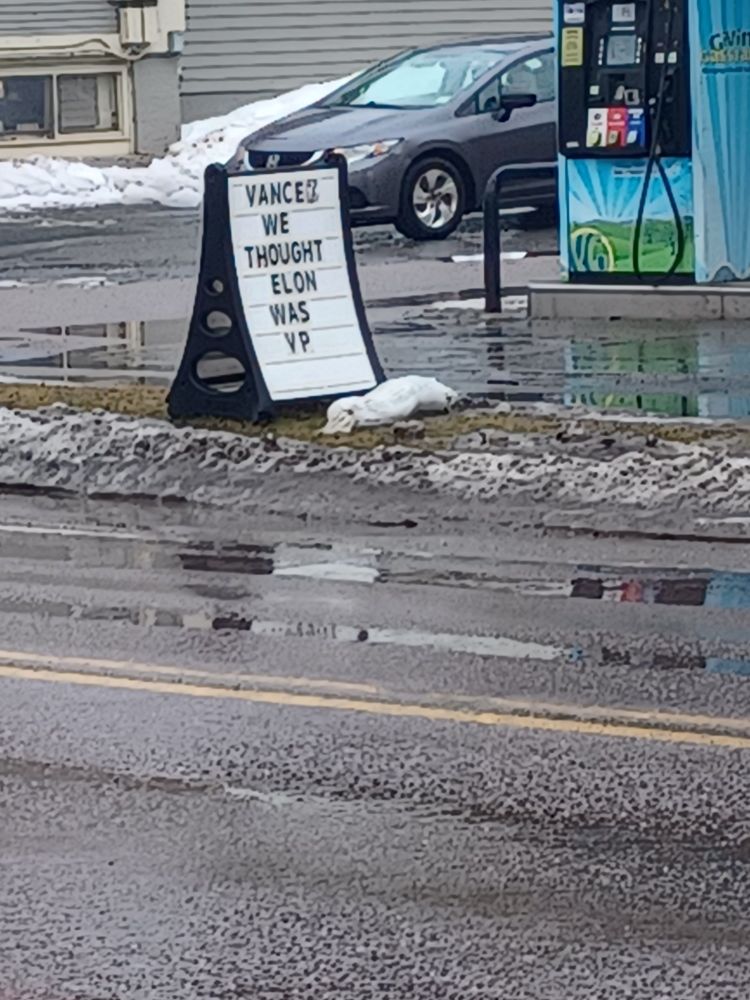 Sidewalk sign that says "Vance? We thought Elon was VP."