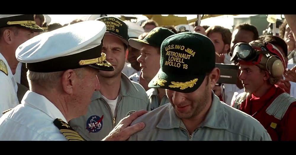 Scrreenshot from the Apollo 13 movie, showing the real Jim Lovell, playing the part of the captain of the USS Iwo Jima greeting Tom Hanks playing him. 