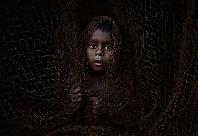 Un bambino avvolto in una rete.
ph Abhishek Basak, Trapped in Silence