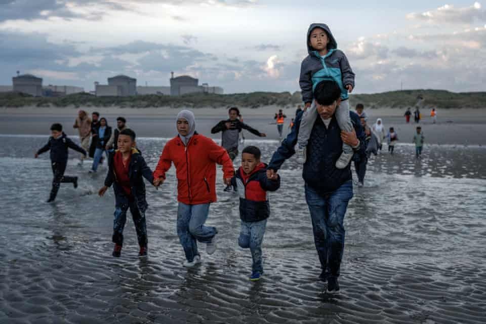 Un gruppo di migranti entra in acqua per imbarcarsi.
