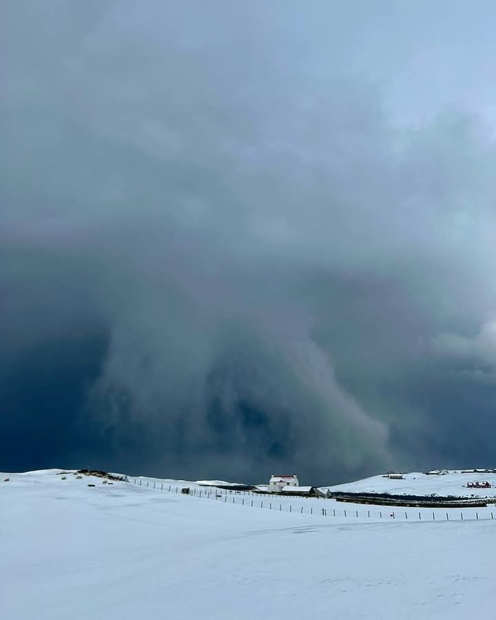 Nuvole scure incombono su un paesaggio innevato.