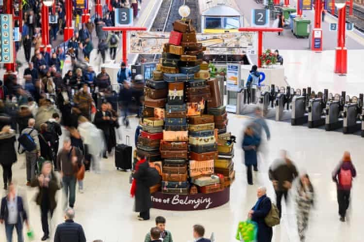 Un albero di Natale, formato da valigie,  situato all'interno di una stazione ferroviaria. 