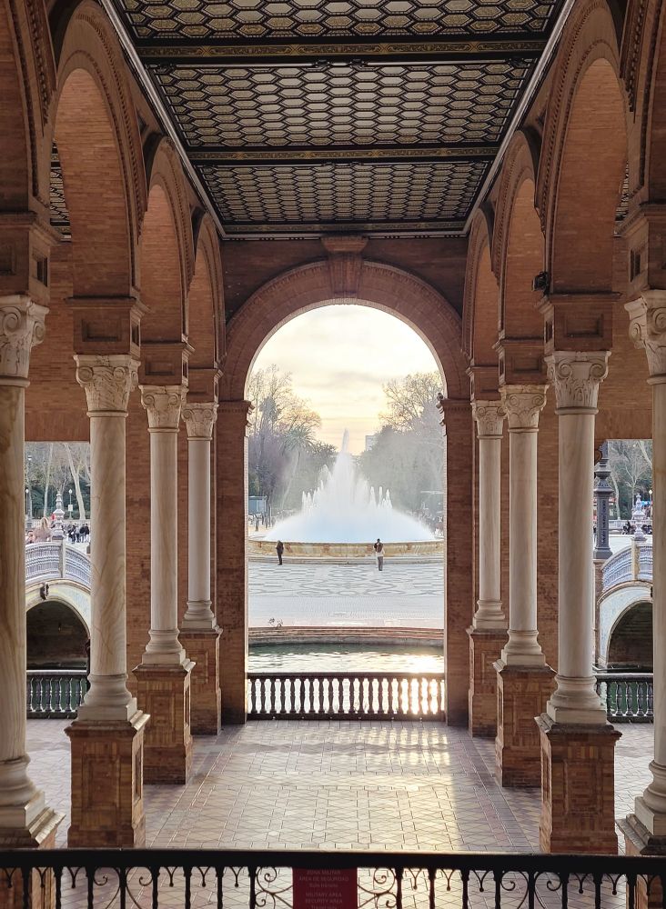 View through the arches to the fountain at sunset in the Plaza de España, Seville 