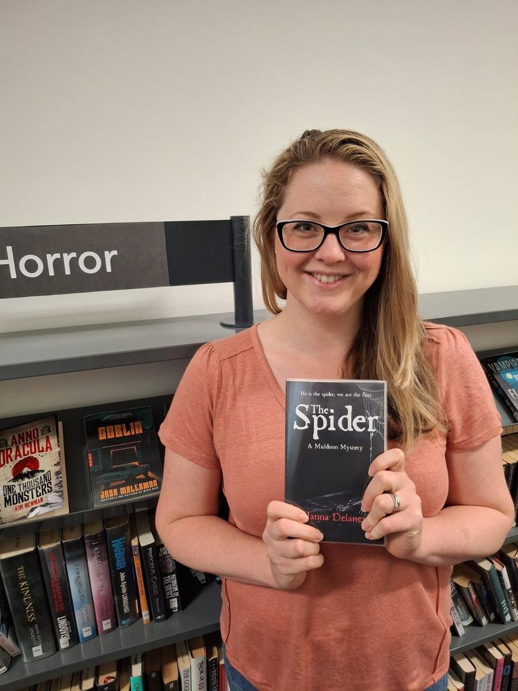 Hanna is holding a copy of The Spider. It is a black paperback book. 