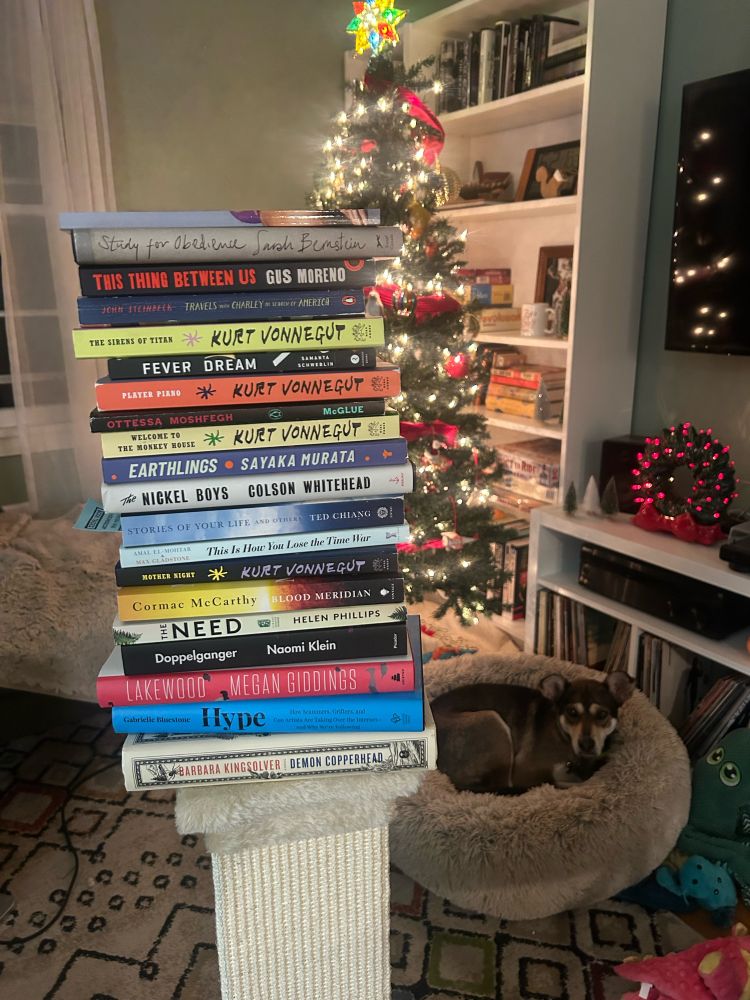 A stack of books with a dog and tree in the background. 