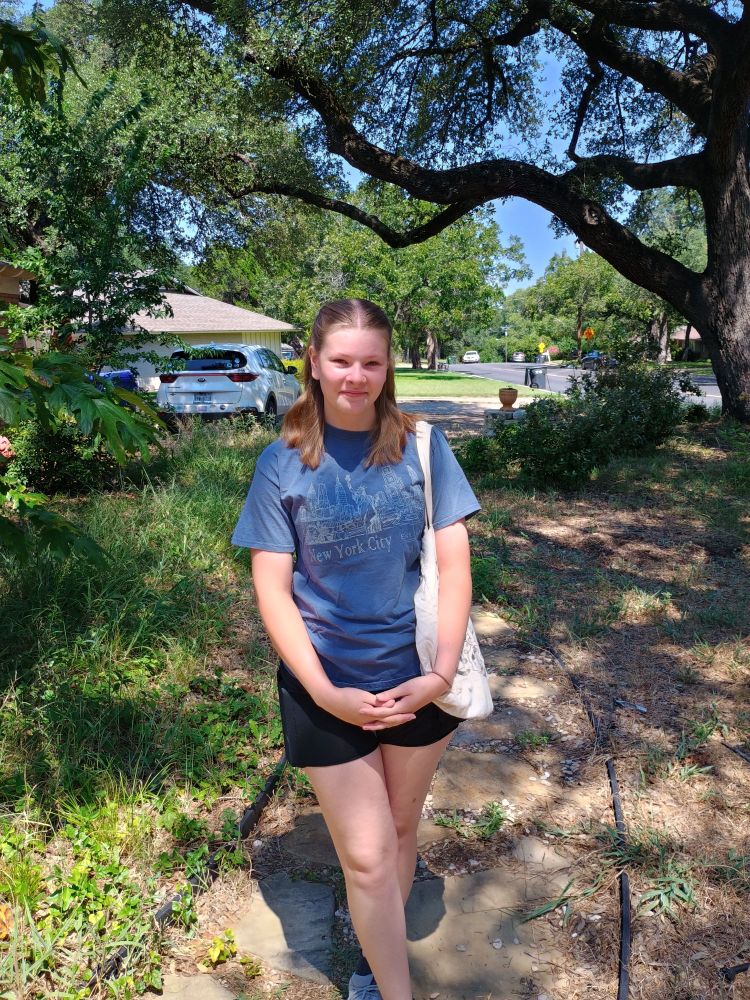 A young blonde woman standing in her yard on her first day as a college student