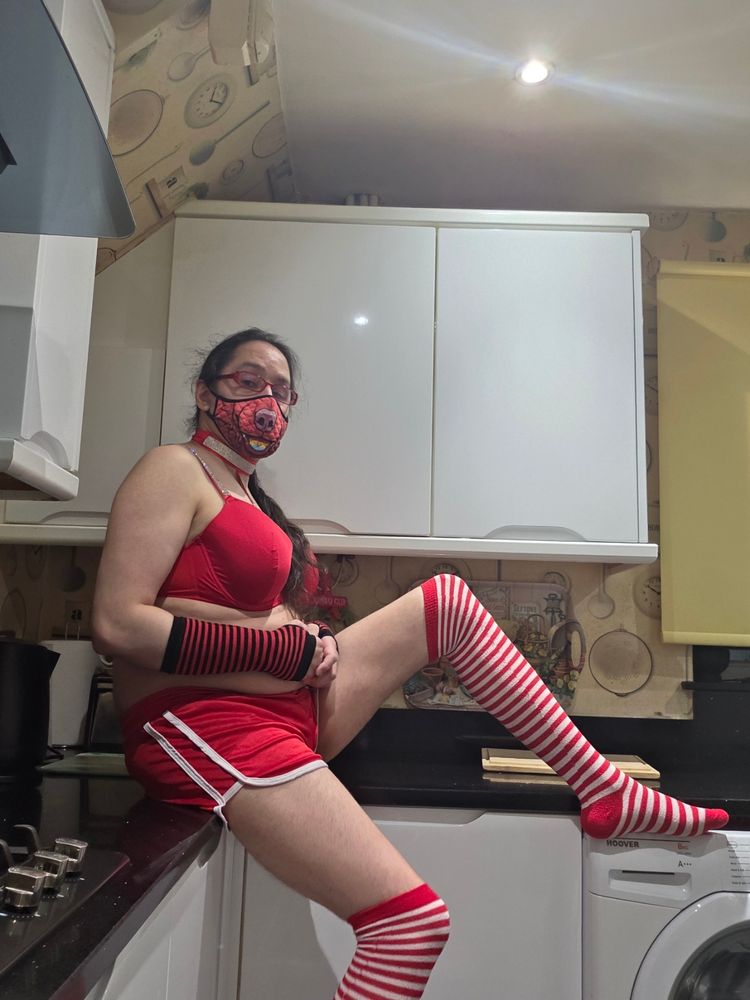 IRL Sparky wearing a red bra with a detatchable collar; also wearing red and white striped over-the-knee socks, red and black striped below-the-elbow arm warmers, all while sitting on the kitchen top counter in a very relaxed position