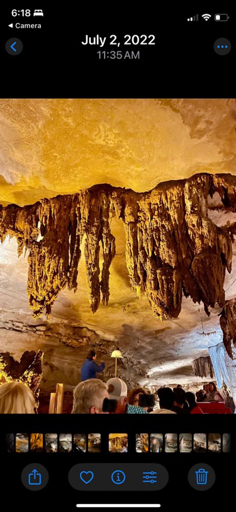 A guided cave tour with visitors gazing up at large, jagged stalactites hanging from a warmly lit cavern ceiling. A guide in blue gestures toward the formations. #FantatsicCaverns #Soringfield #artyear #photography #Americana 