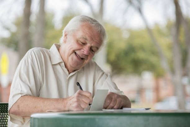 Un vieil homme souriant en écrivant une lettre