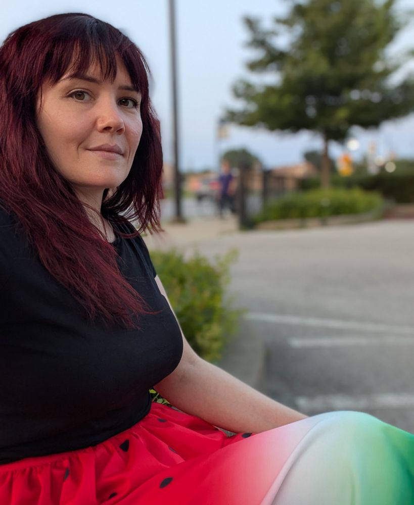 Me sitting in a parking lot wearing a skirt with a print that looks like a watermelon 