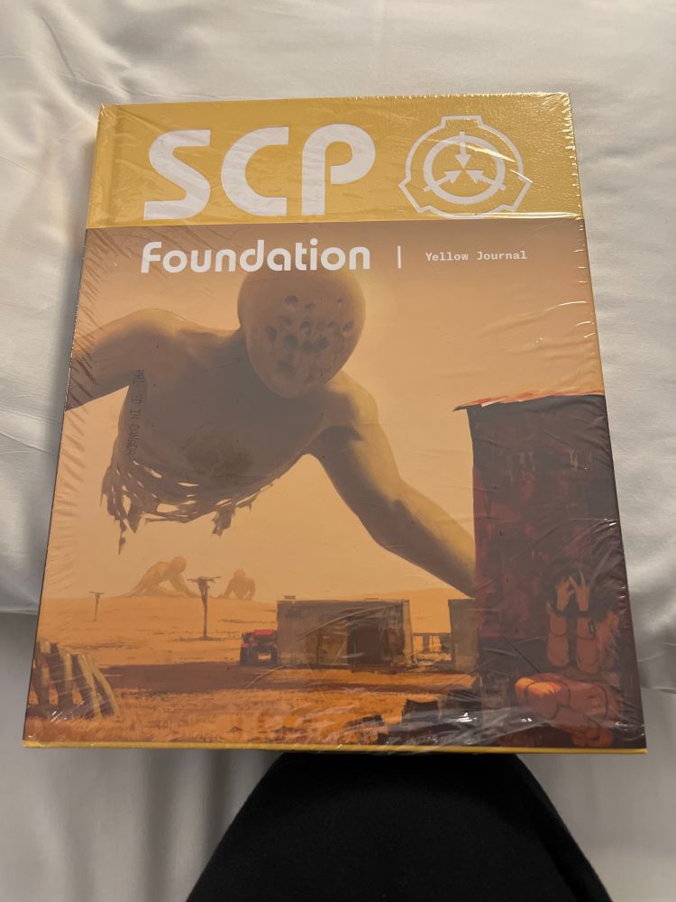 Cover of yellow SCP art book, showing a giant humanoid monster looming over an SCP scientist in a desert  
